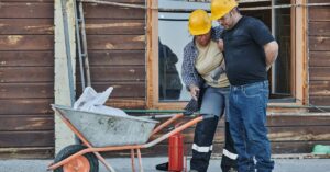 Trabalhador de construção sendo auxiliado por colega após acidente de trabalho