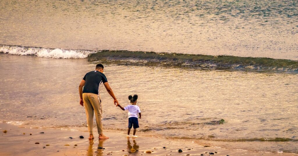 Pai e filho de mãos dadas na praia representando guarda compartilhada