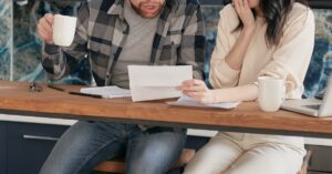 Casal preocupado analisando documentos financeiros sobre dívidas