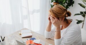 Mulher revisando contas e calculadora simbolizando situação de dívidas e mínimo existencial