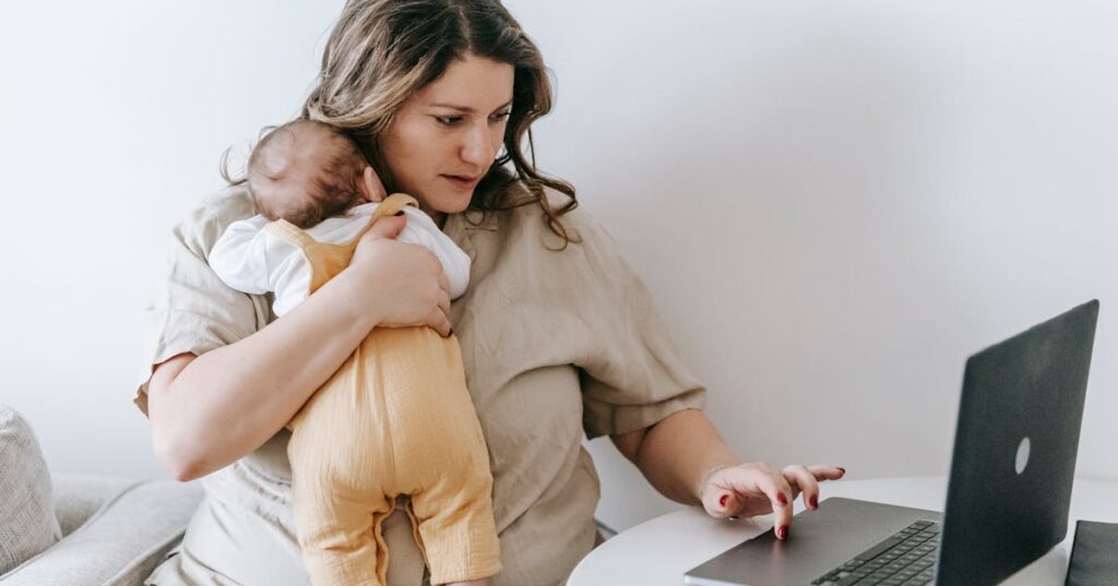 Mãe com bebê consultando notebook representando pensão alimentícia