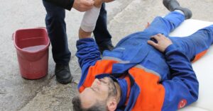 Trabalhador adulto com o braço lesionado recebendo atendimento, ilustrando o auxílio-acidente do INSS