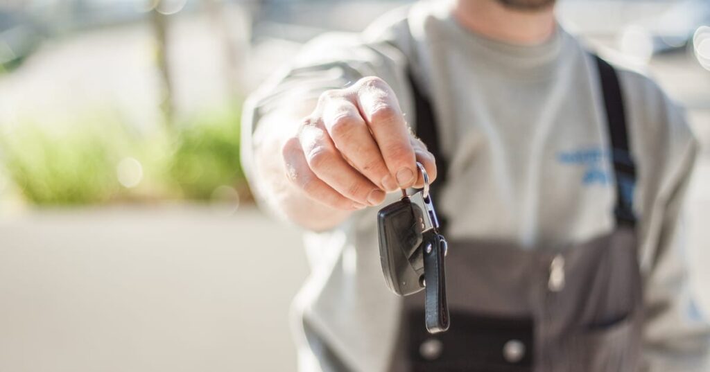 Homem adulto segurando a chave de um carro, representando proprietário de veículo financiado