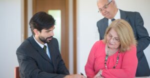 Casal de herdeiros assinando documentos de inventário com advogado em escritório