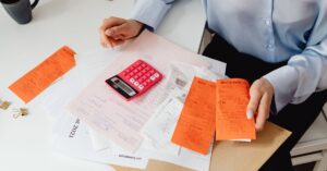 Adulto revisando contas e contrato bancário com calculadora sobre a mesa