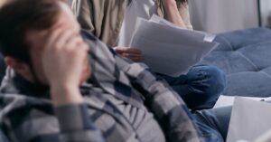 Casal adulto revisando contas e dívidas em casa, tema da Lei do Superendividamento