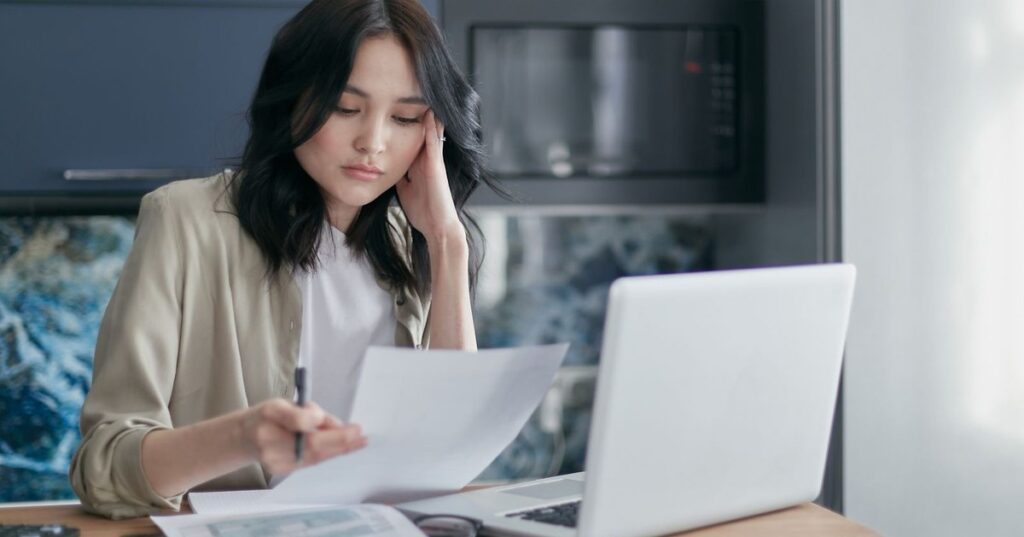 Pessoa adulta revisando contas e cartao de credito preocupada com negativacao indevida