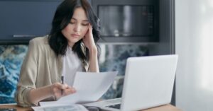 Pessoa adulta revisando contas e cartao de credito preocupada com negativacao indevida
