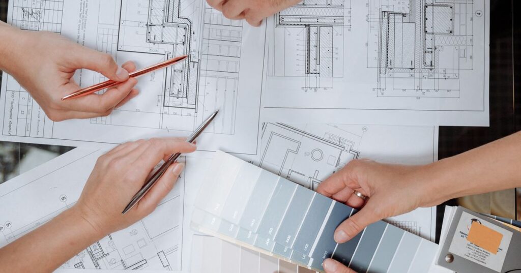 Profissionais adultos analisando plantas e projeto de construcao de imovel