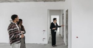 Casal adulto visitando apartamento em obra com corretor, representando compra de imóvel na planta