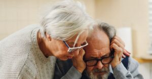 Casal idoso analisando documentos e faturas de plano de saúde sobre a mesa