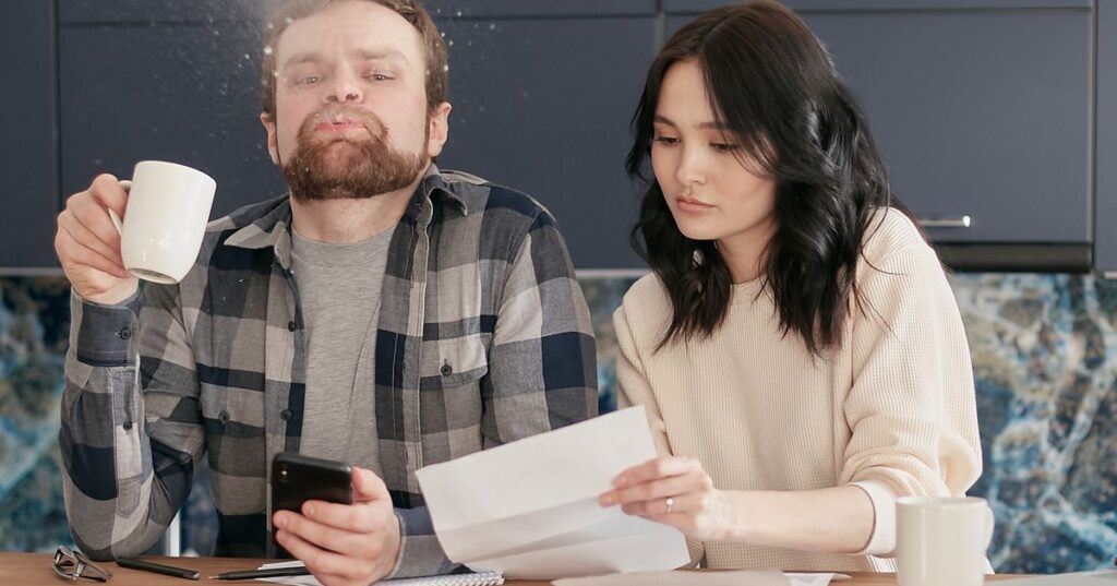 Casal adulto revisando contas e documentos financeiros sobre a mesa