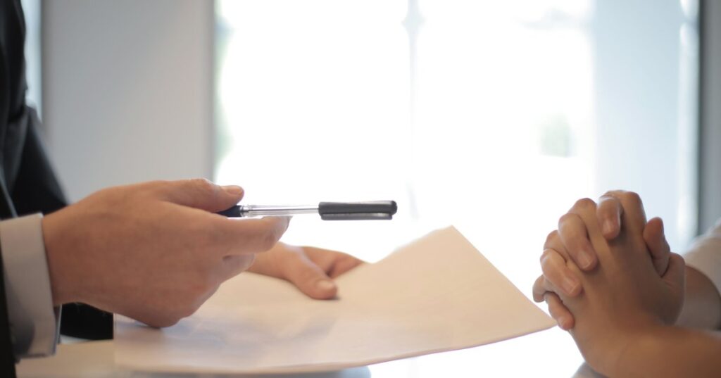 Profissional entregando contrato e caneta para cliente assinar empréstimo