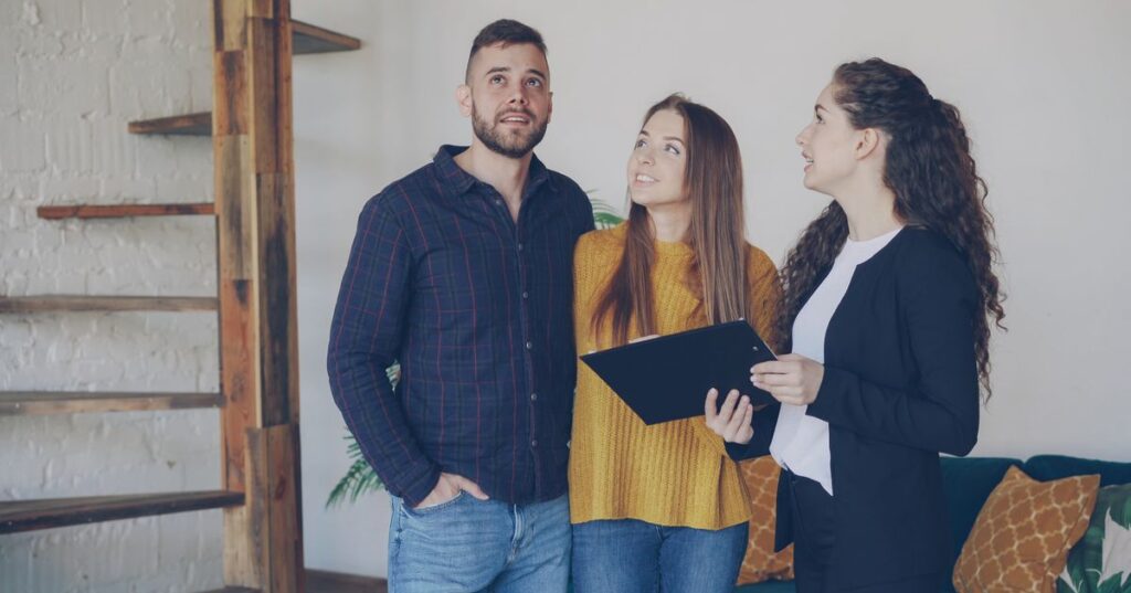 Casal adulto vistoriando imóvel novo com corretora, tema vícios construtivos