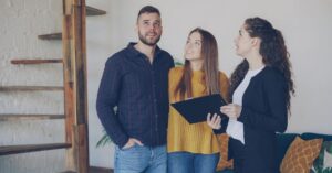 Casal adulto vistoriando imóvel novo com corretora, tema vícios construtivos