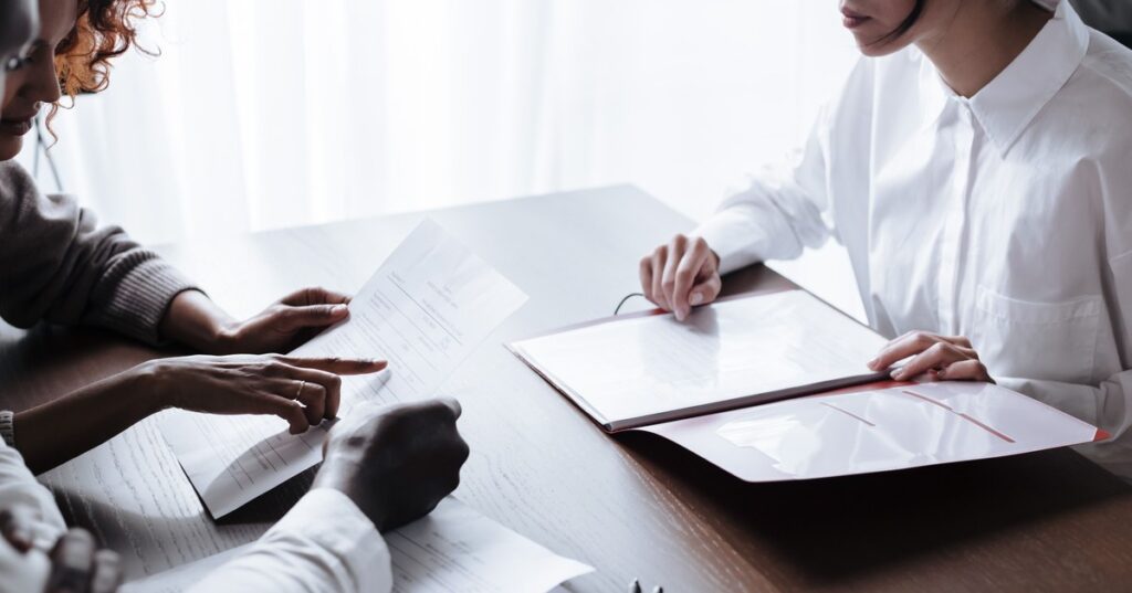 Casal adulto revisando contrato de consorcio com profissional sobre a mesa