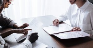 Casal adulto revisando contrato de consorcio com profissional sobre a mesa