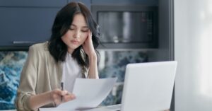 Mulher adulta revisando documentos e contas sobre dívidas deixadas em inventário