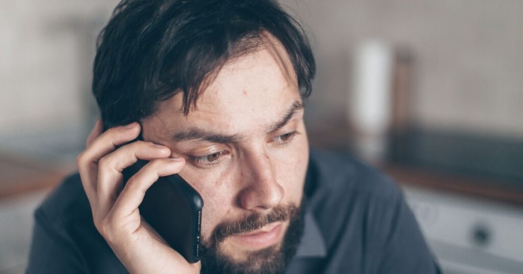 Homem adulto preocupado ao telefone apos golpe do Pix