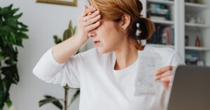 Mulher adulta preocupada revisando contas e comprovantes em casa