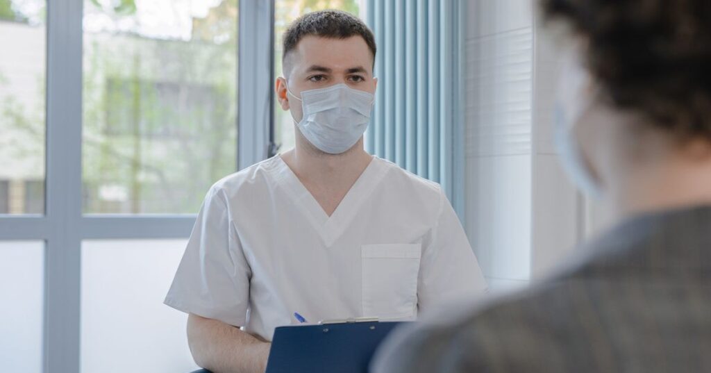 Paciente adulto em consulta médica enquanto profissional de saúde faz anotações em prancheta