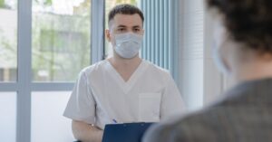 Paciente adulto em consulta médica enquanto profissional de saúde faz anotações em prancheta