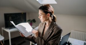 Mulher adulta revisando documentos de contrato e apólice de seguro